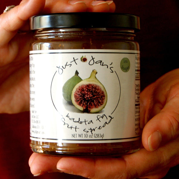 Person holding a jar of fig spread with a visible label.